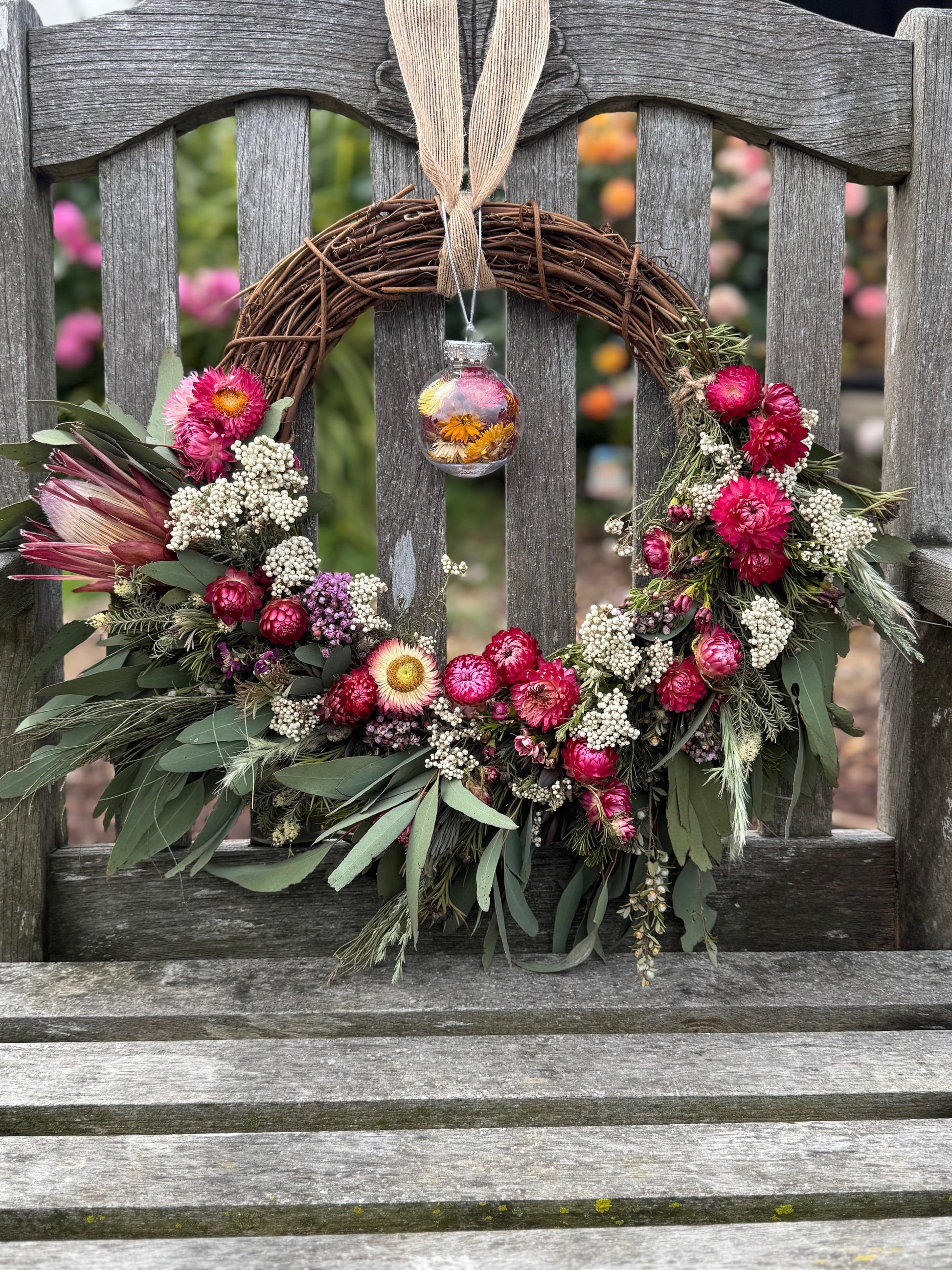 Decorative native eucalyptus and strawflower wreath with flowers and a hanging ornament 